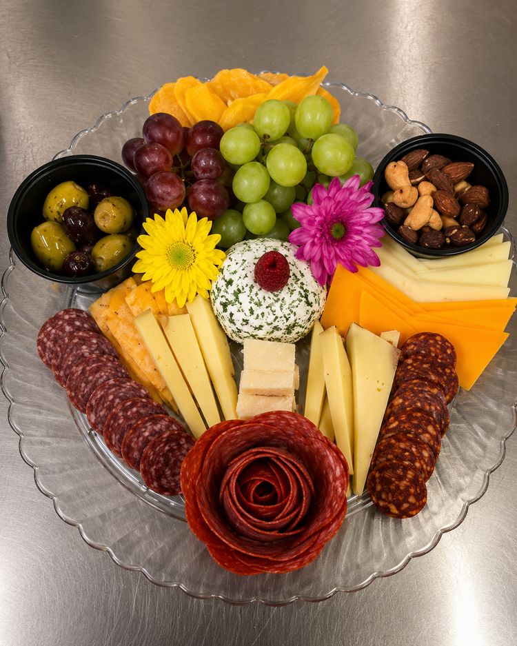 Meat and cheese tray with grapes, olives, nuts and a salami rose