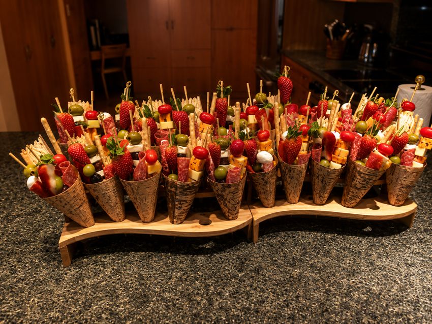 Appetizer cones with skewered fruit and cheese on a wooden display stand